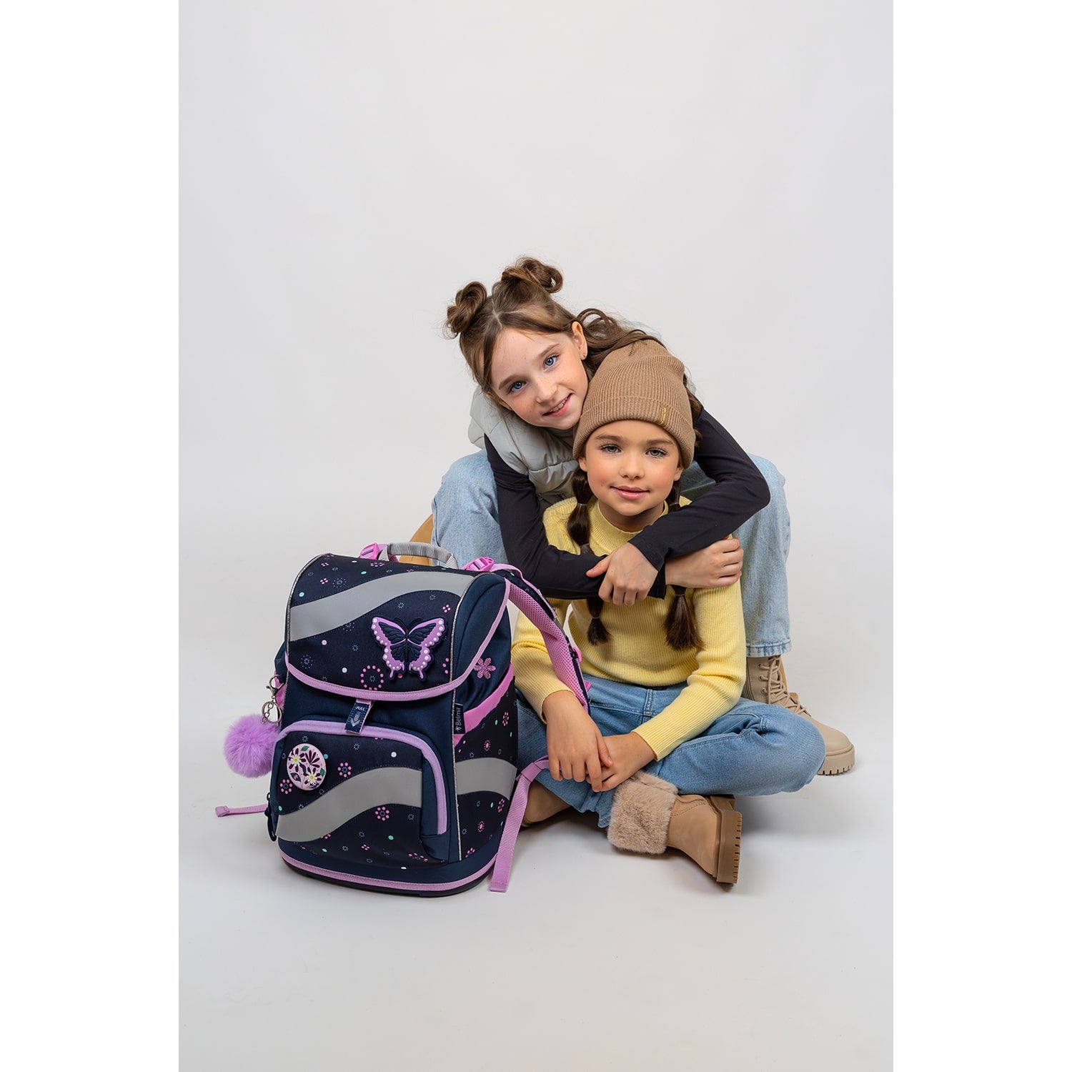 Girl holding the Belmil Smarty Flowers Blue Ergonomic School Bag Set for Girls – 5-Piece Set with 9 Patches and Hip Belt with her school supplies.