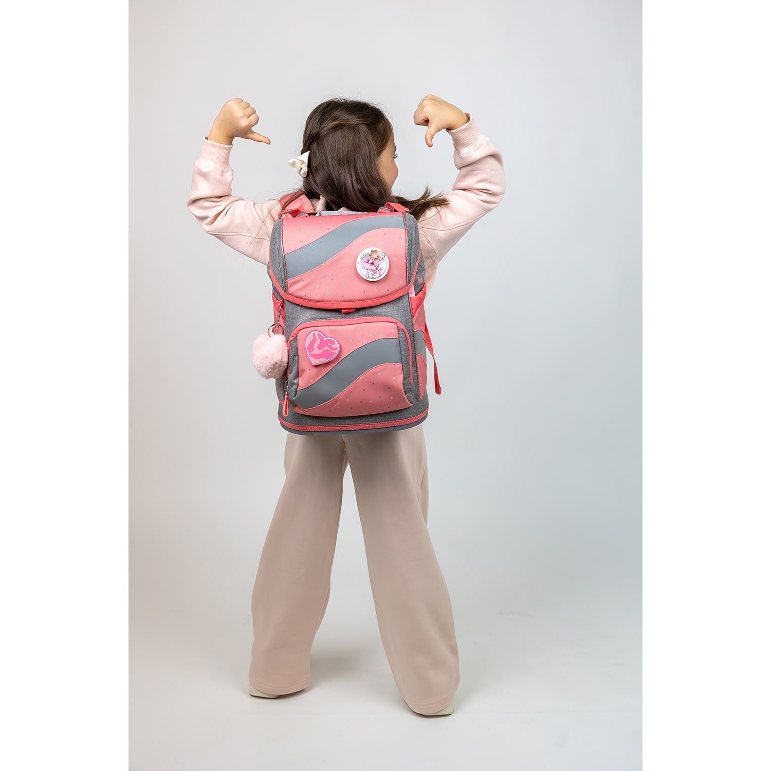 A young girl proudly displays the Belmil Smarty Minimal Triangels Ergonomic School Bag Set – 5-Piece Set with 9 Interchangeable Patches and Hip Belt, showcasing its ergonomic design and stylish appearance.